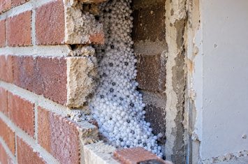 Spouwmuurisolatie met EPS-parels in de muur van een woning Spouwmuur van een woning gevuld met EPS-parels voor thermische isolatie
